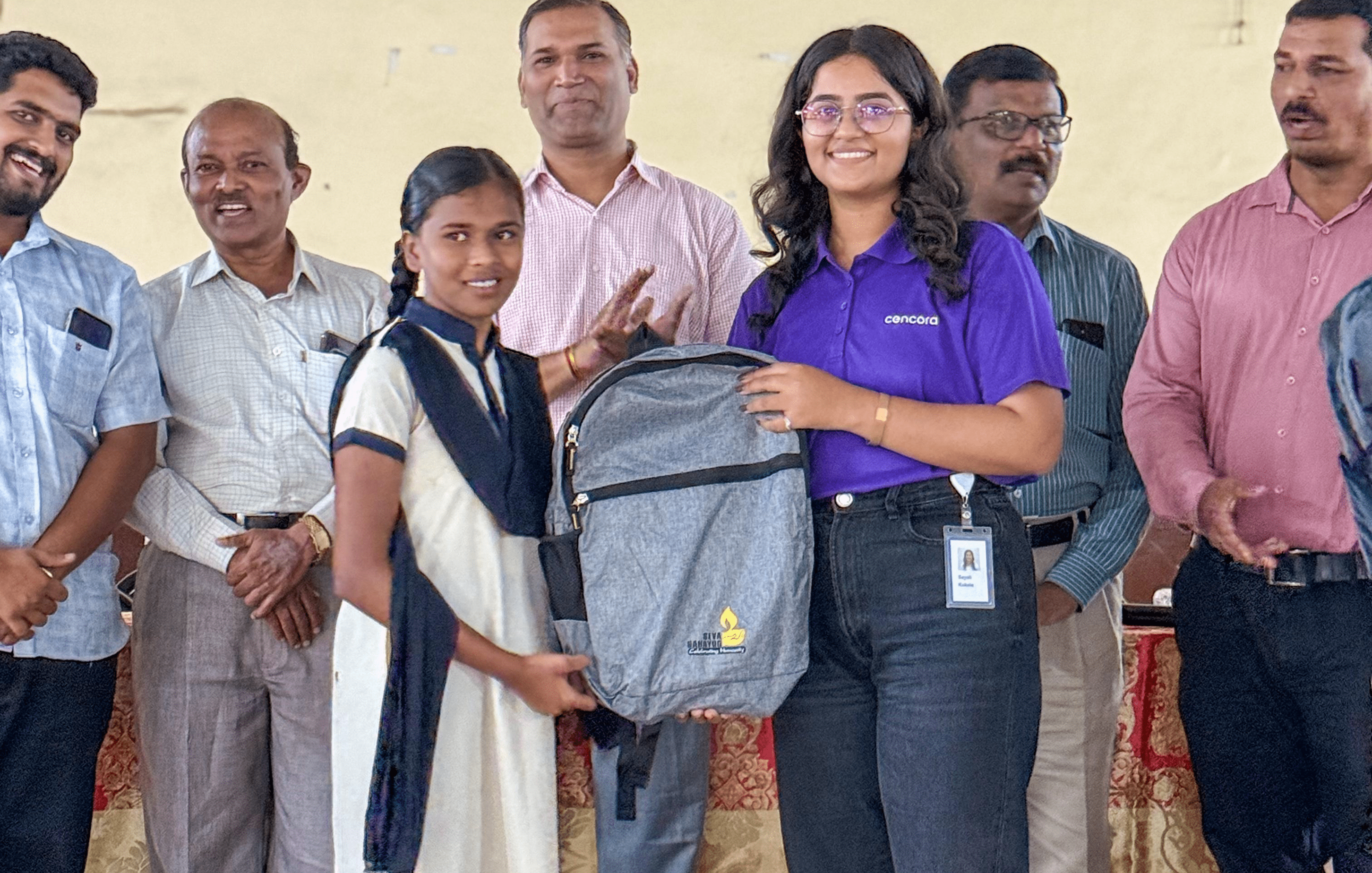 Group of people standing close to each other and showing a backpack.